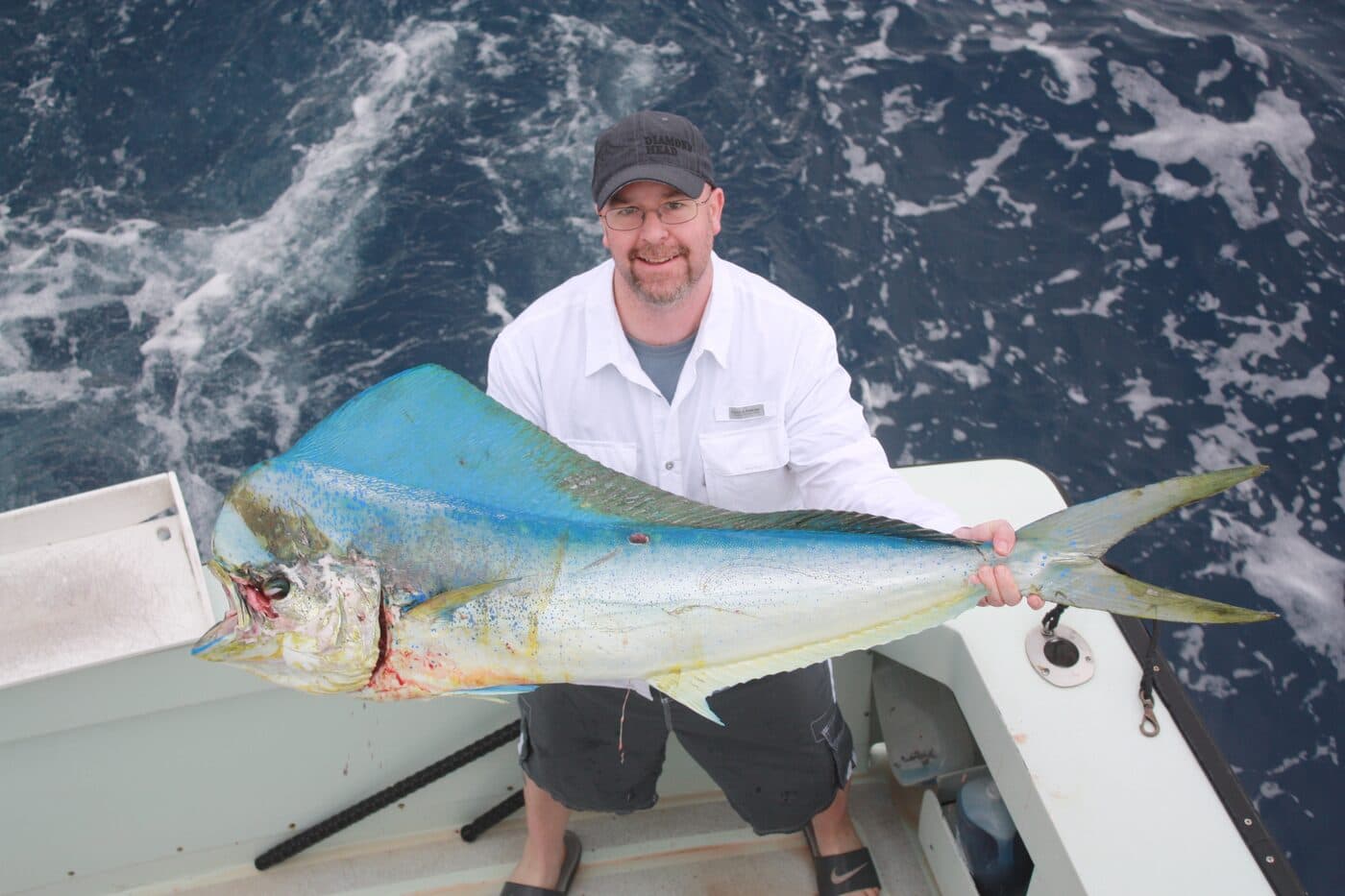 An angler holding a mahimahi in the cockpit