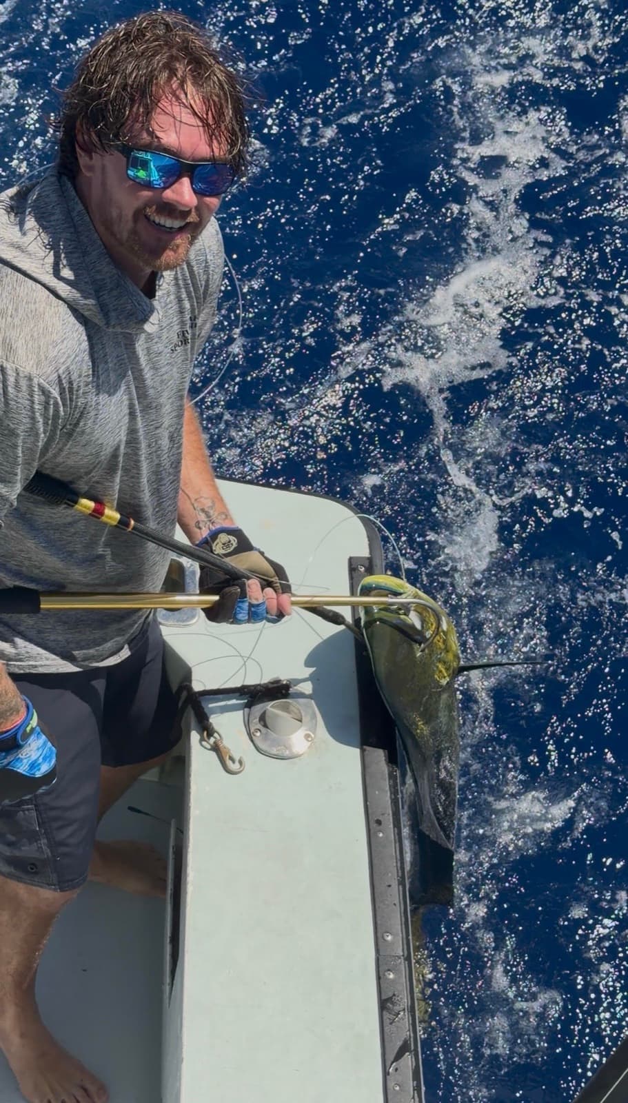 Capt. Dallas Bock grinning with a gaff in hand on the side of Ruckus