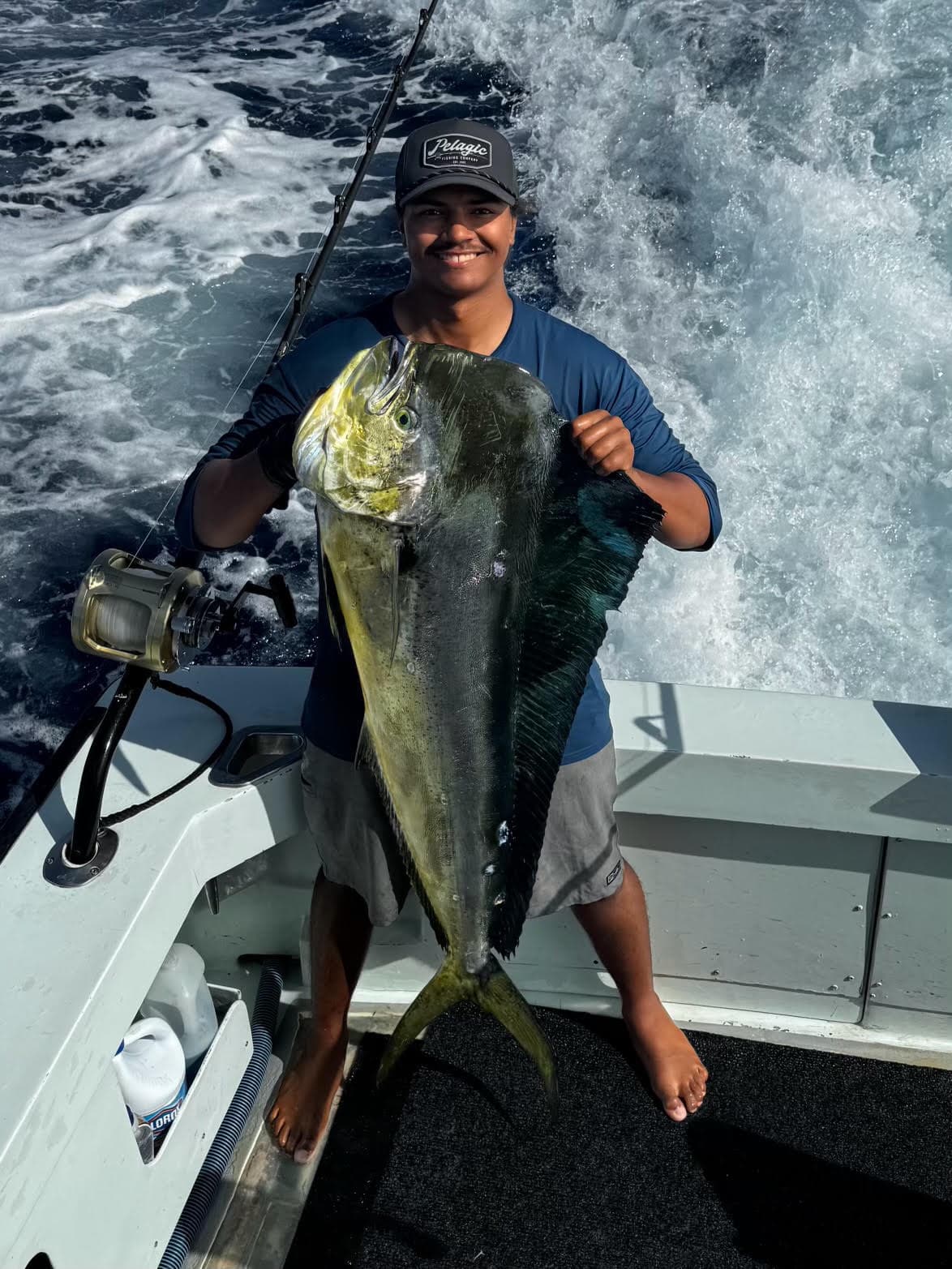 First mate Tino Rose holding up a bull mahimahi in the cockpit of Ruckus